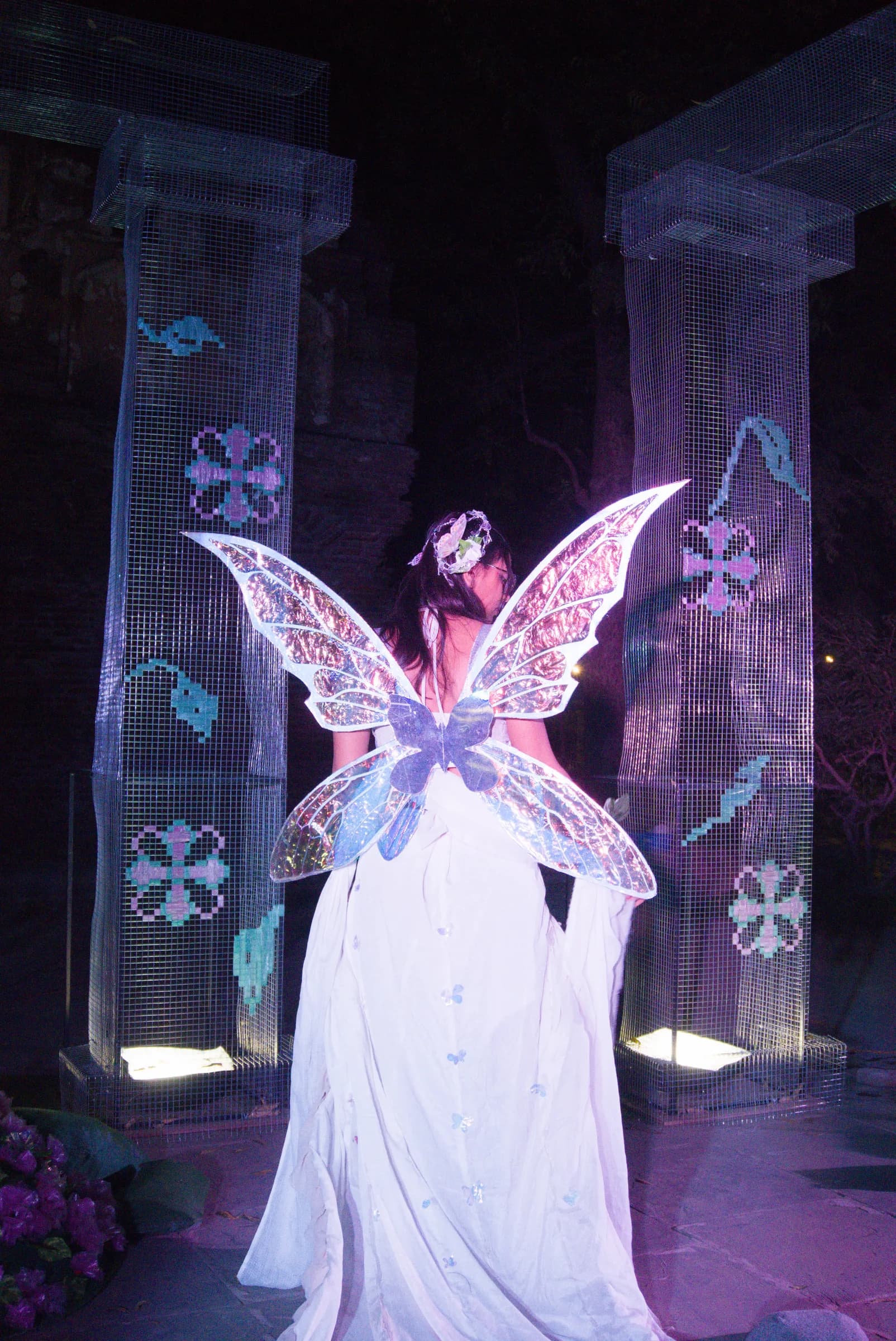 Performer framed by translucent columns and decorative wings