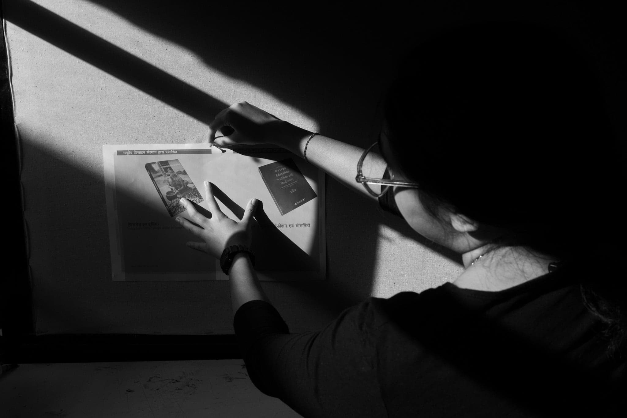 Hands working with images in a shaft of light