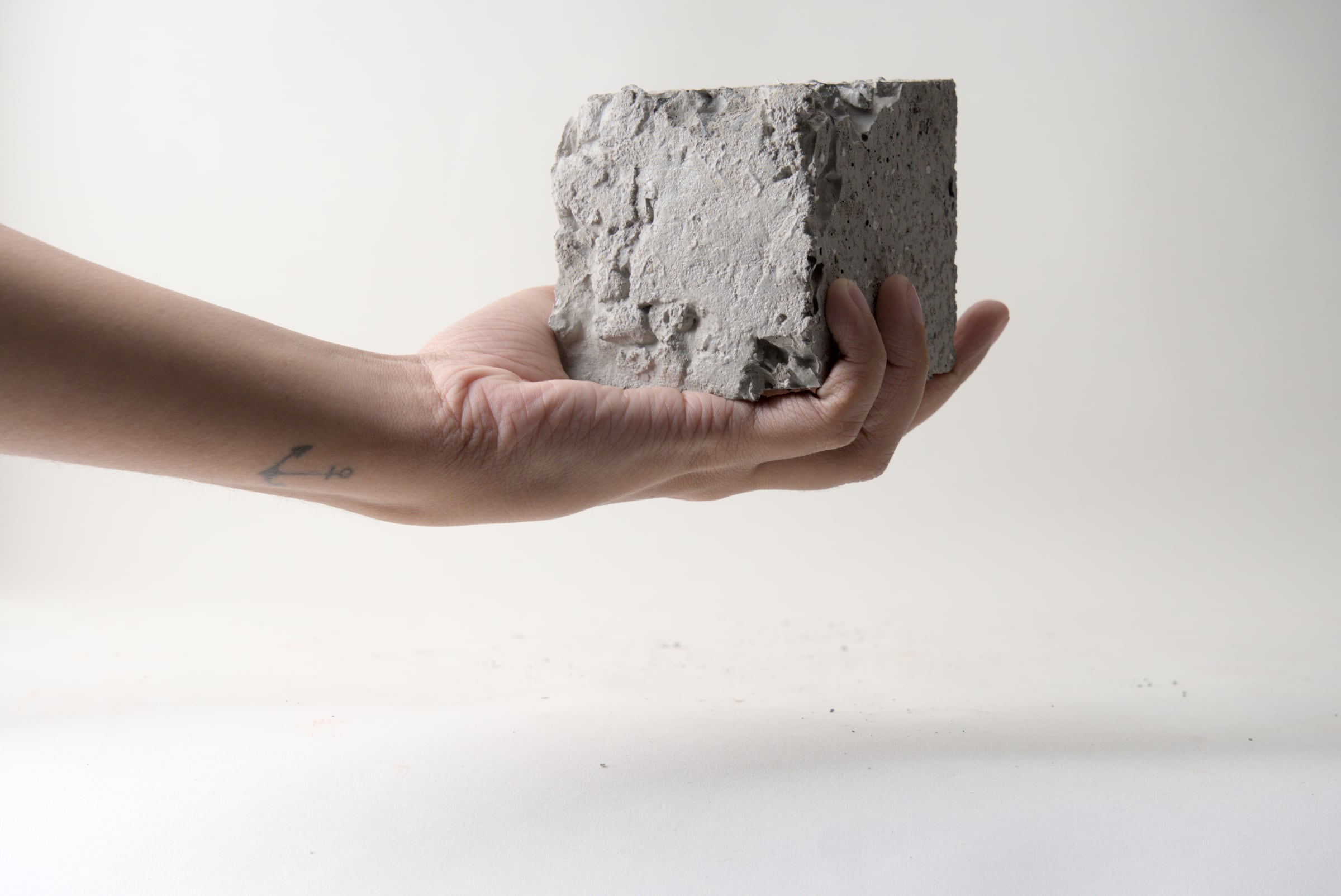 Hand holding a small concrete cube to show scale and texture